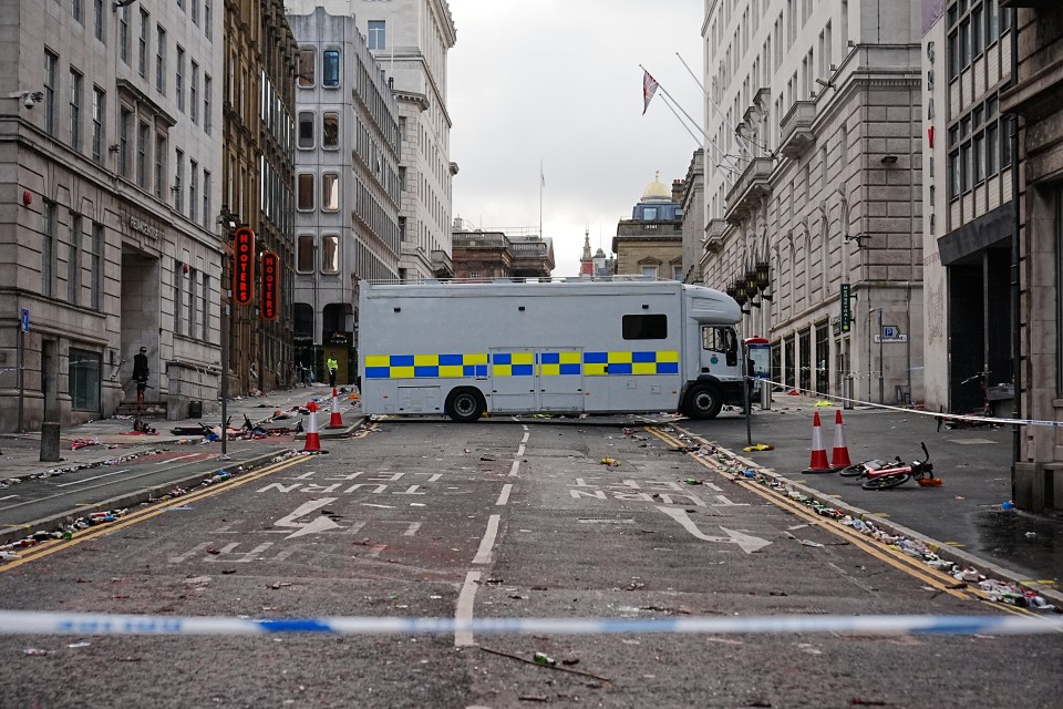 Aftermath of a car plowing into a crowd in Liverpool, showing debris and a police vehicle.