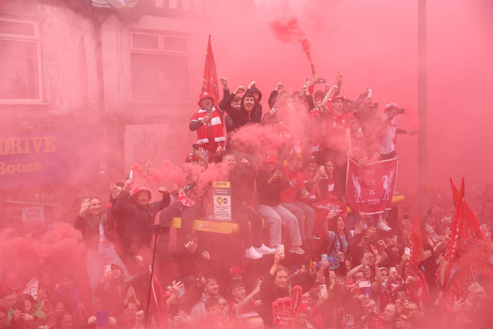Liverpool fans celebrating in red smoke at a victory parade.