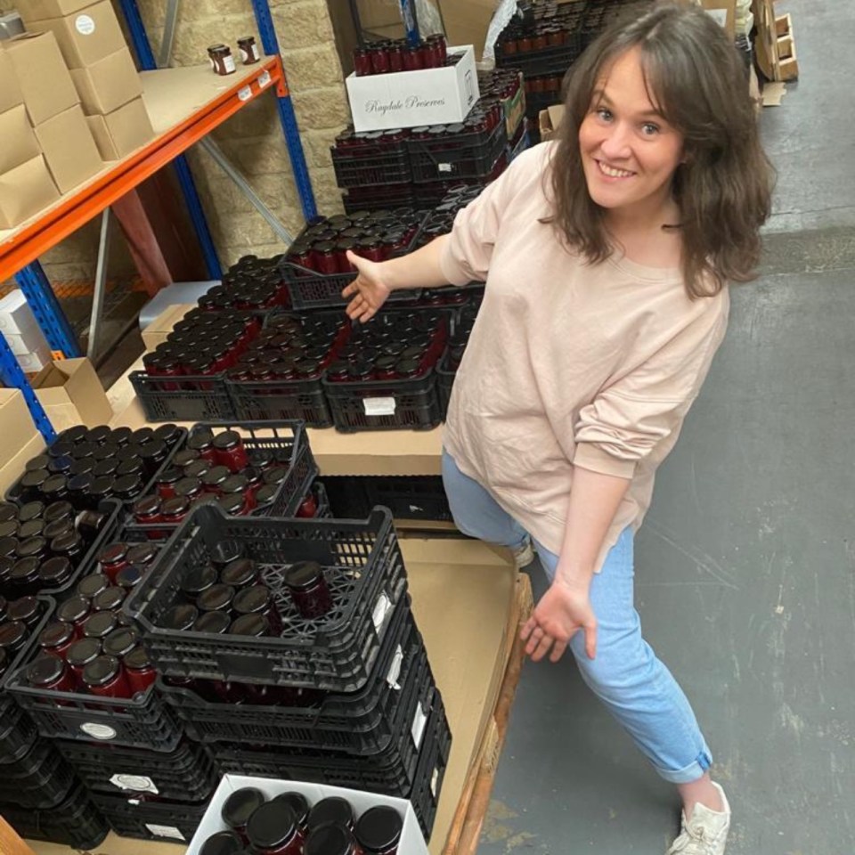 Woman standing in warehouse next to many crates of jars.