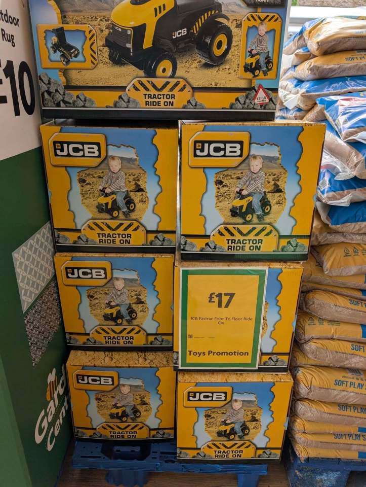 Stack of JCB tractor ride-on toy boxes in a supermarket.