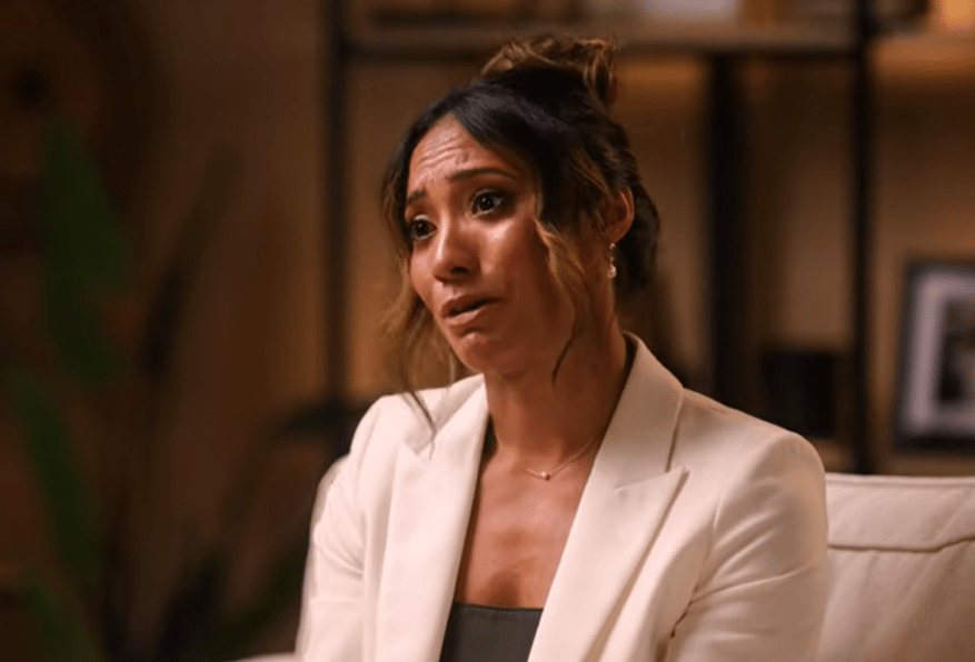 Woman in a white blazer, looking upset.