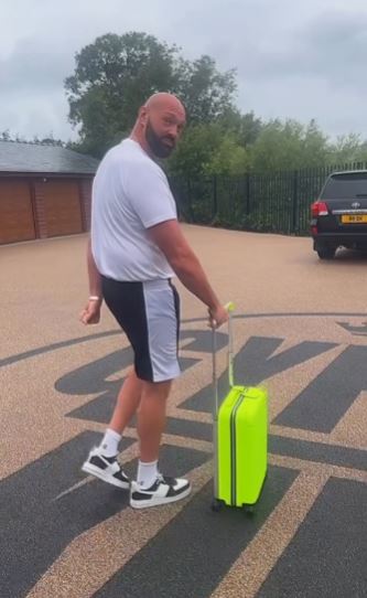 Tyson Fury pulling a bright green suitcase.