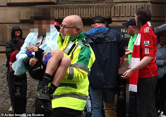 Emergency services rushed to the scene and 27 people, including four children, were taken to hospitals across the city. Pictured: A paramedic carries an injured child out the crowd