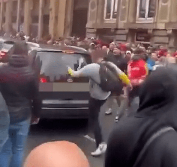 Person kicking a car in a crowd.