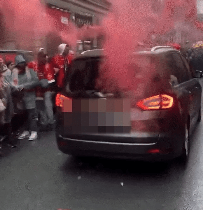People celebrating in red smoke around a car.