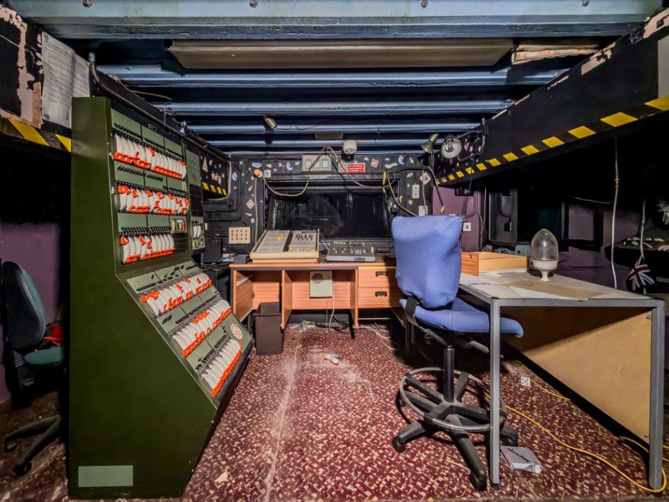 Control room of an abandoned theatre, filled with old equipment.