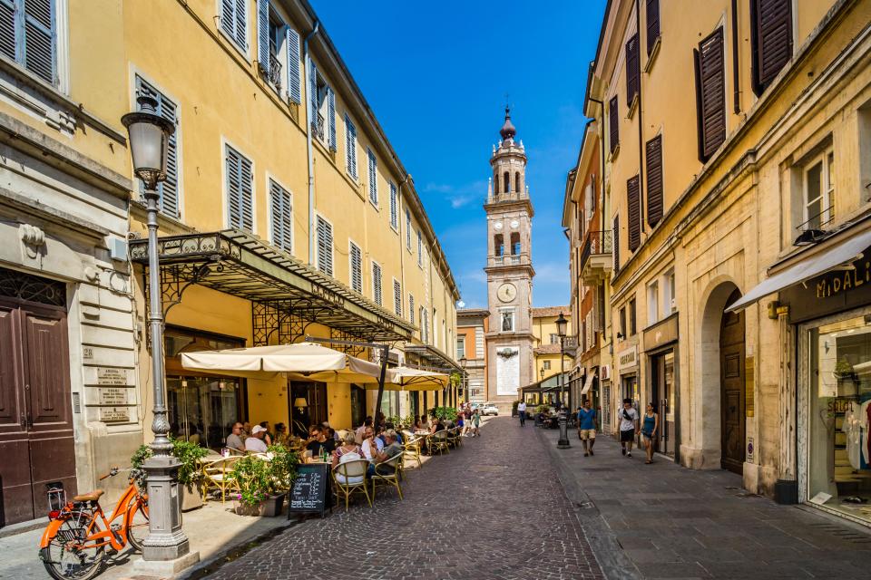 Tourists enjoying a charming historic street in Parma, Italy.
