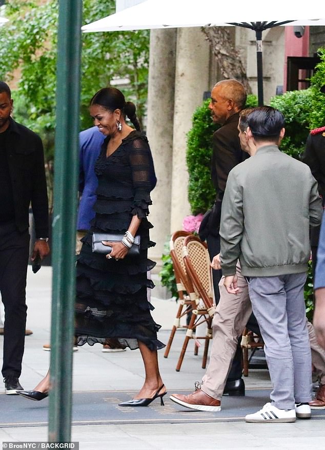 Dressed black dress and black heels, Michelle, 61, appeared to flash a broad smile while husband Barack, 63, looked pensive