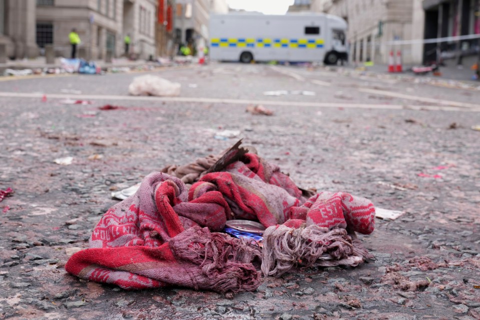 A blood-stained fan scarf lies on the ground amidst debris.