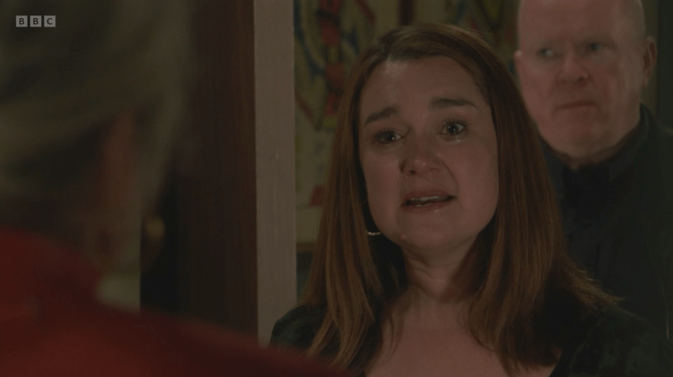 Screenshot of a woman crying, with a man standing behind her.