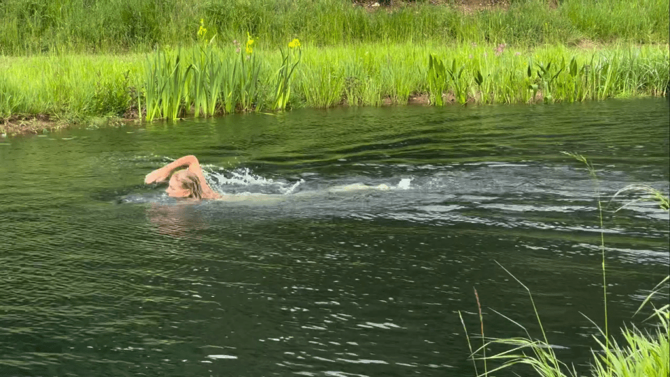 Woman swimming naked in a lake.
