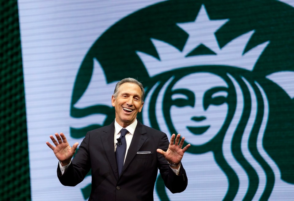 Howard Schultz speaking in front of the Starbucks logo.