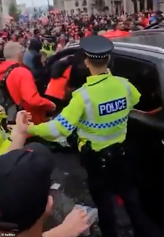 The crowd scramble to bring the car to a stop as bystanders lean into the vehicle