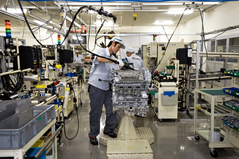 Worker assembling a car engine on a factory assembly line.