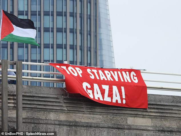 A red banner dangles over the railings with the words 'Stop Starving Gaza!' written on the front
