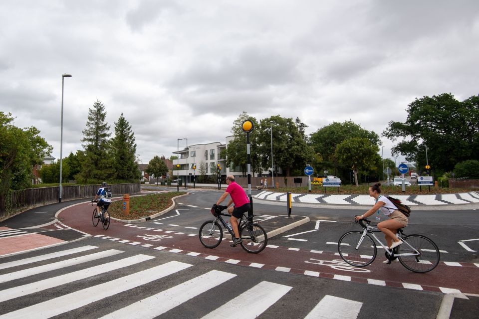 Cyclists using a Dutch-style roundabout with designated cycle lanes and pedestrian crossings.