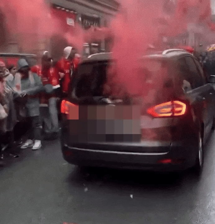 Car surrounded by people releasing red smoke.