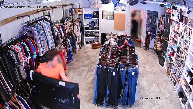 The man is seen calmly walking out past customers during the middle of the day