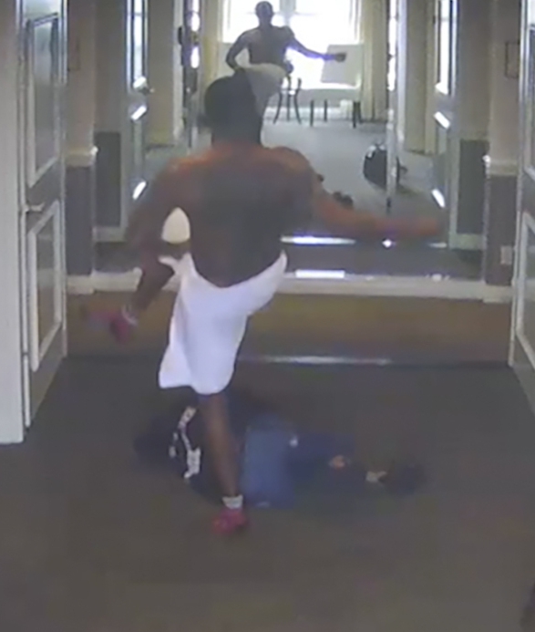 Frame grab from hotel security video showing a man kicking a person lying on the floor.