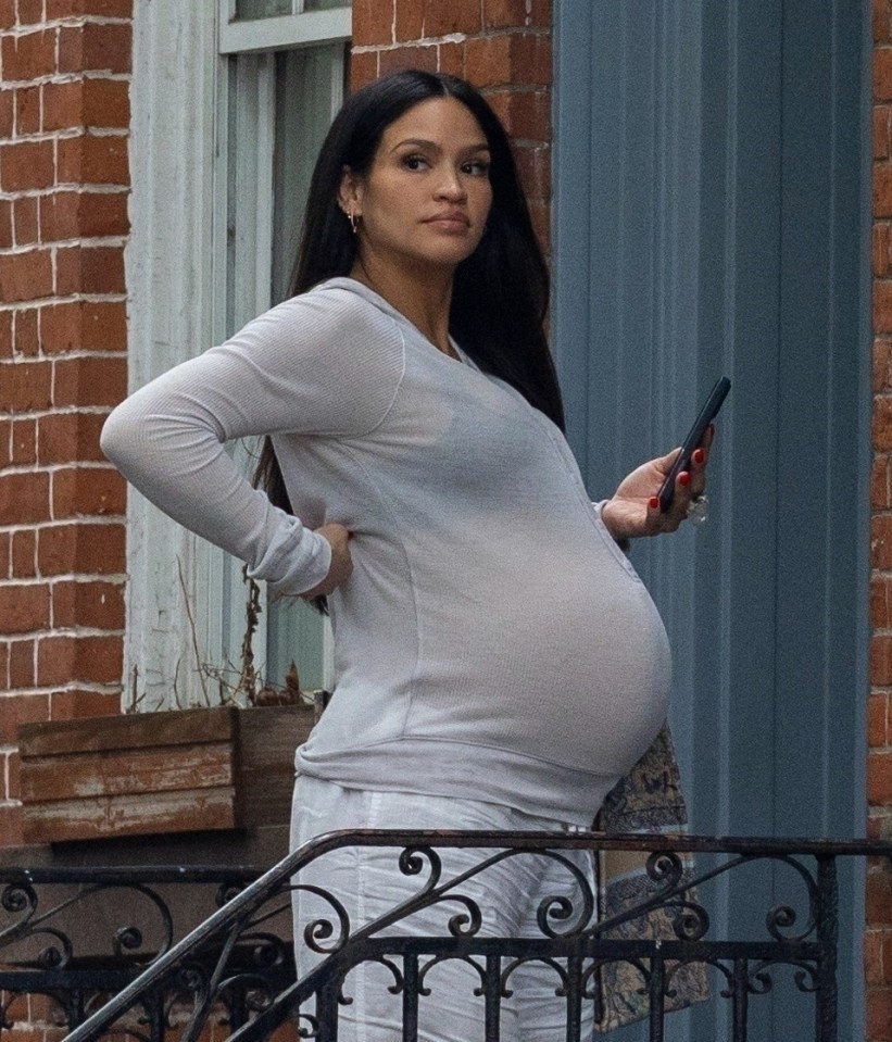 Cassie Ventura, pregnant, using a cell phone outside a building.