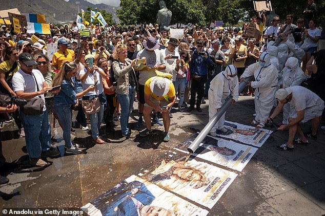 Several activists stage a performance, pouring waste and sewage water on Canary Islands politicians, as thousands of people are protesting against the tourism model and mass tourism in the Canary Islands in Tenefire, Spain on May 18, 2025