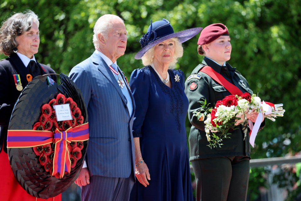 King Charles III and Queen Camilla laying a wreath at a war memorial.