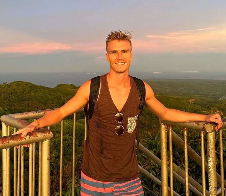 Man smiling at sunset viewpoint.