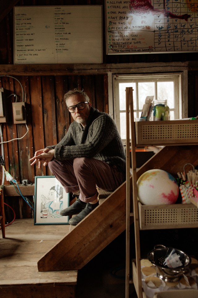 Matt Berninger sitting on stairs in a wooden room.
