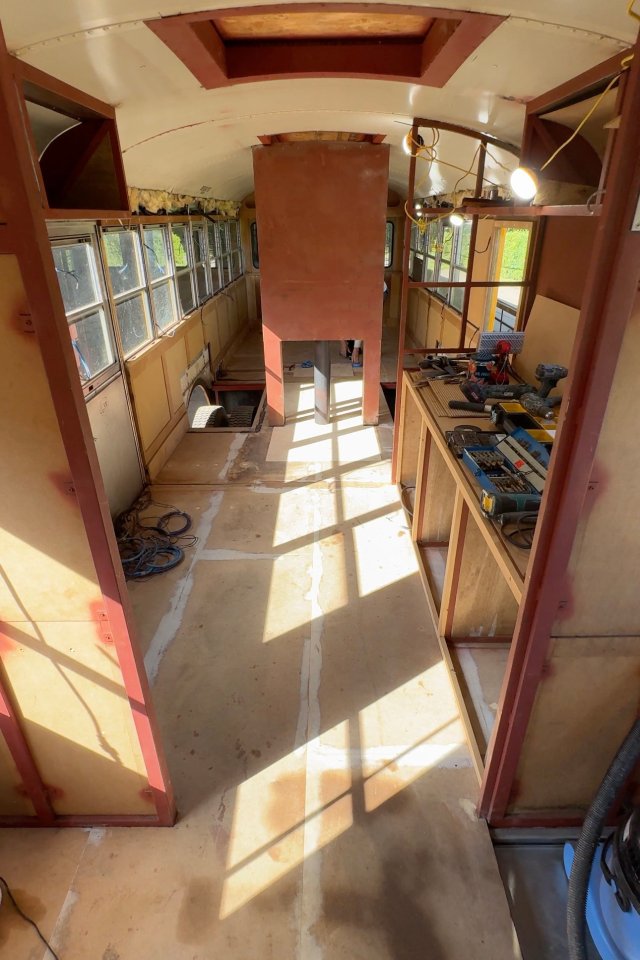 Interior of a renovated school bus, showing the unfinished floor and walls.