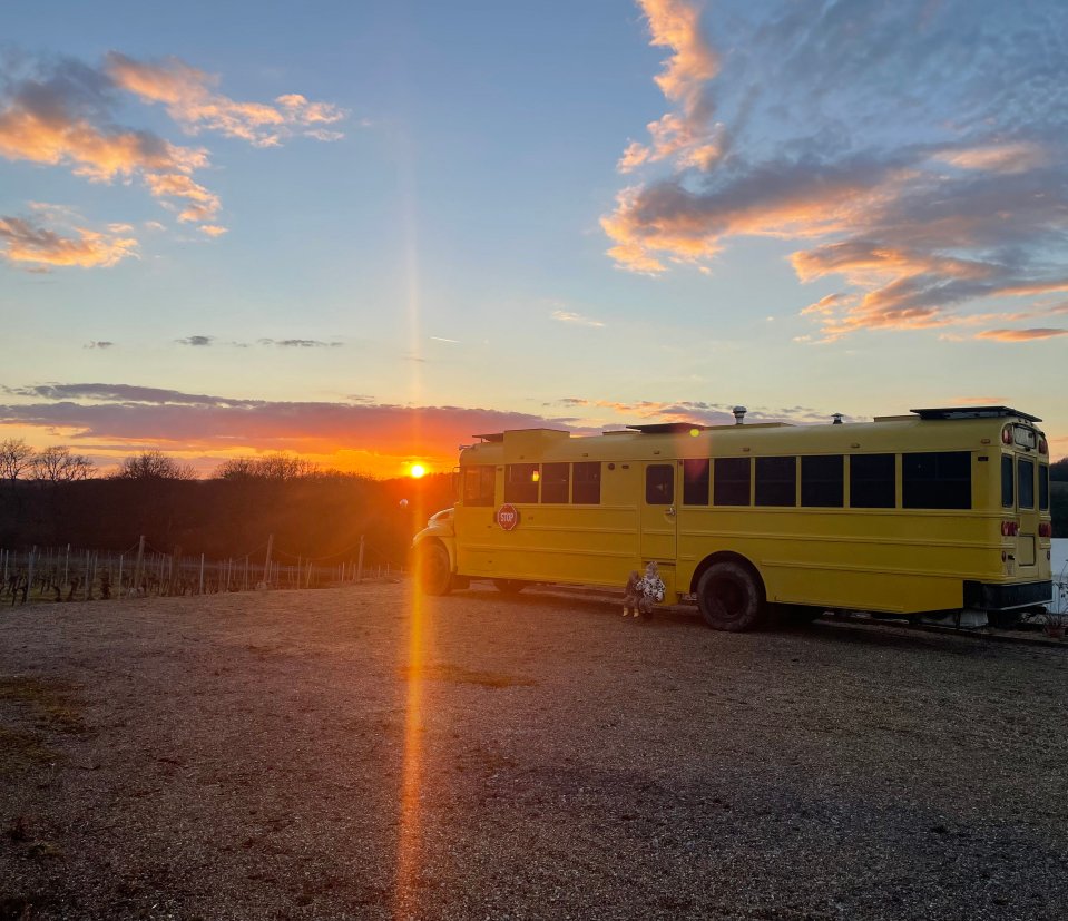 A converted school bus parked at sunset.