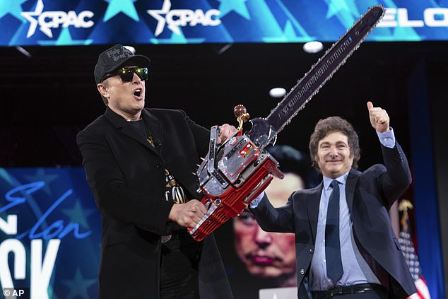 Elon Musk holds up a chainsaw he received from Argentina's President Javier Milei, right, as they arrive to speak at the Conservative Political Action Conference,