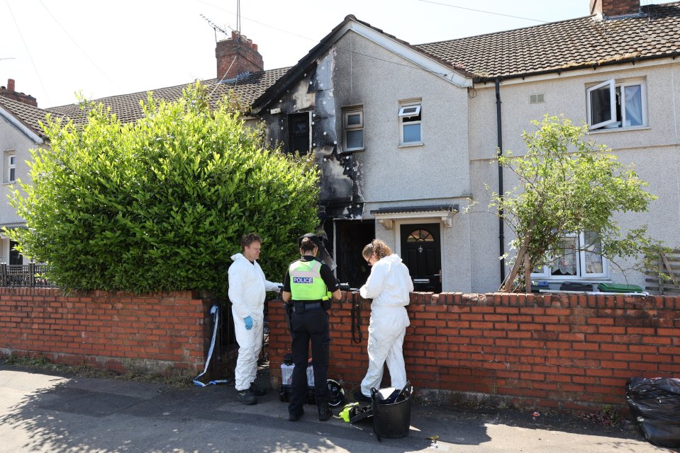 Police officers and forensic investigators at a fire-damaged house.