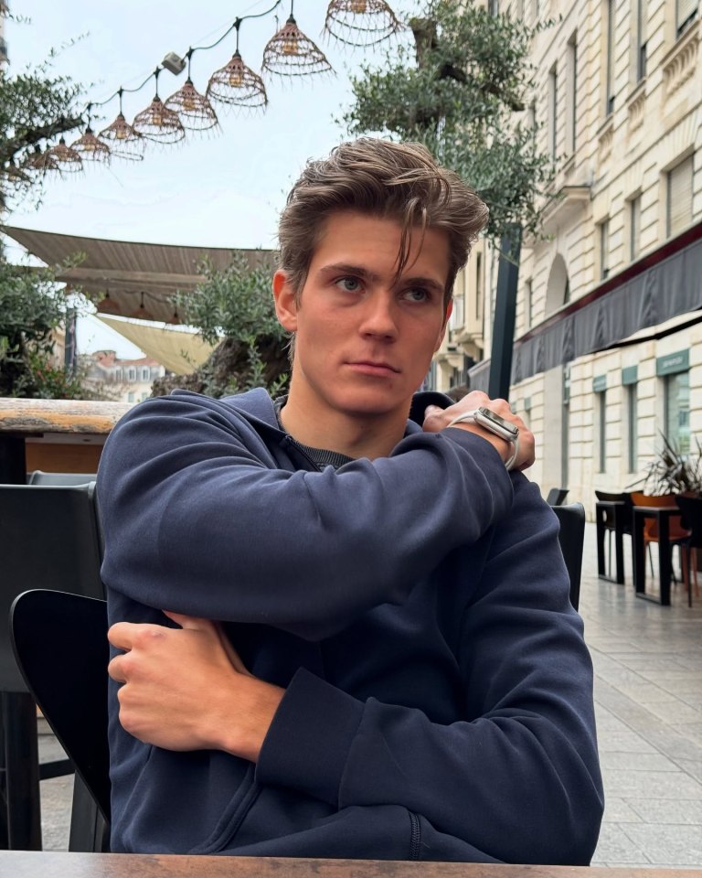 Young man sitting outdoors wearing a dark blue hoodie.
