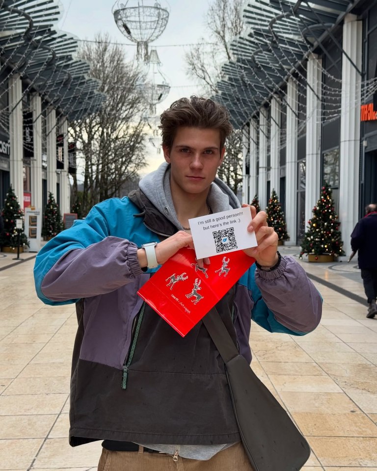 Person holding a red gift bag and a card with a QR code.