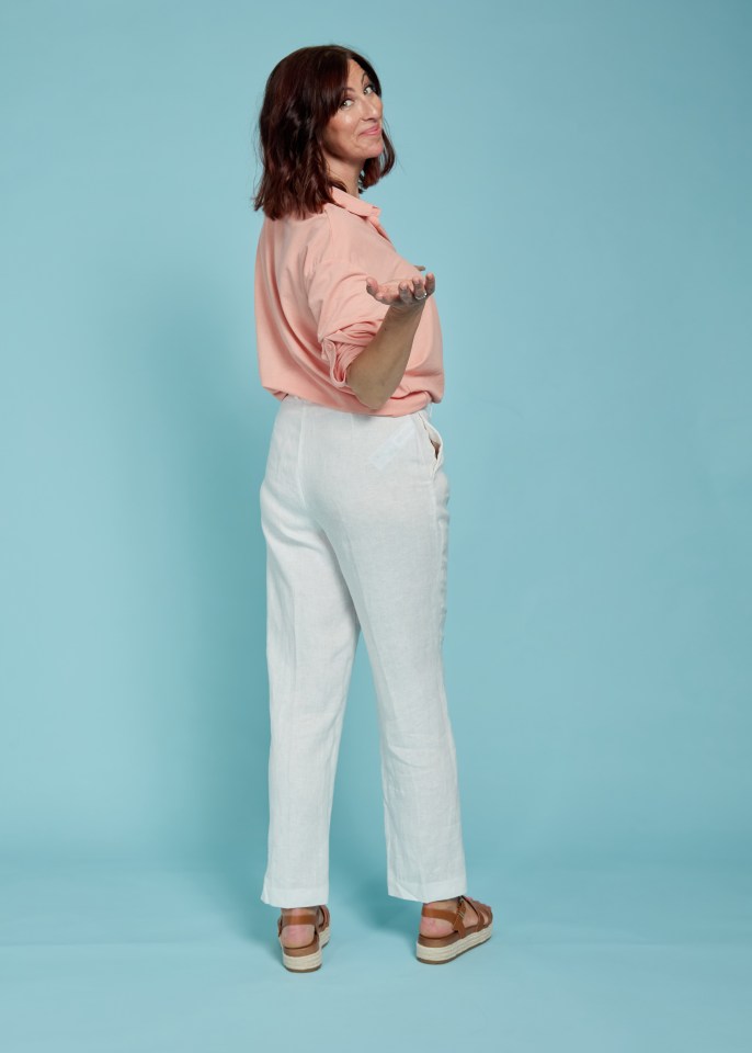 Woman in peach shirt and white pants turning to show her back.