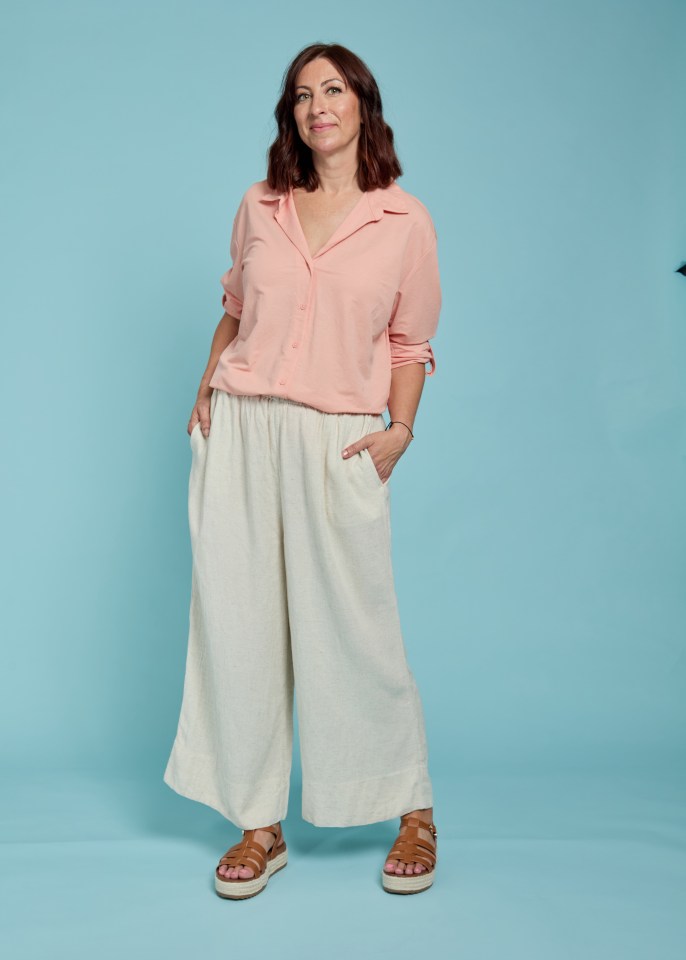 Woman in peach shirt and wide-leg pants.