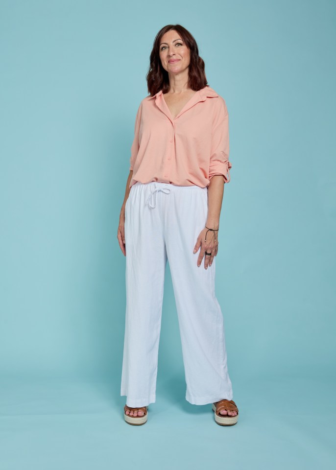 Woman in peach shirt and white trousers.