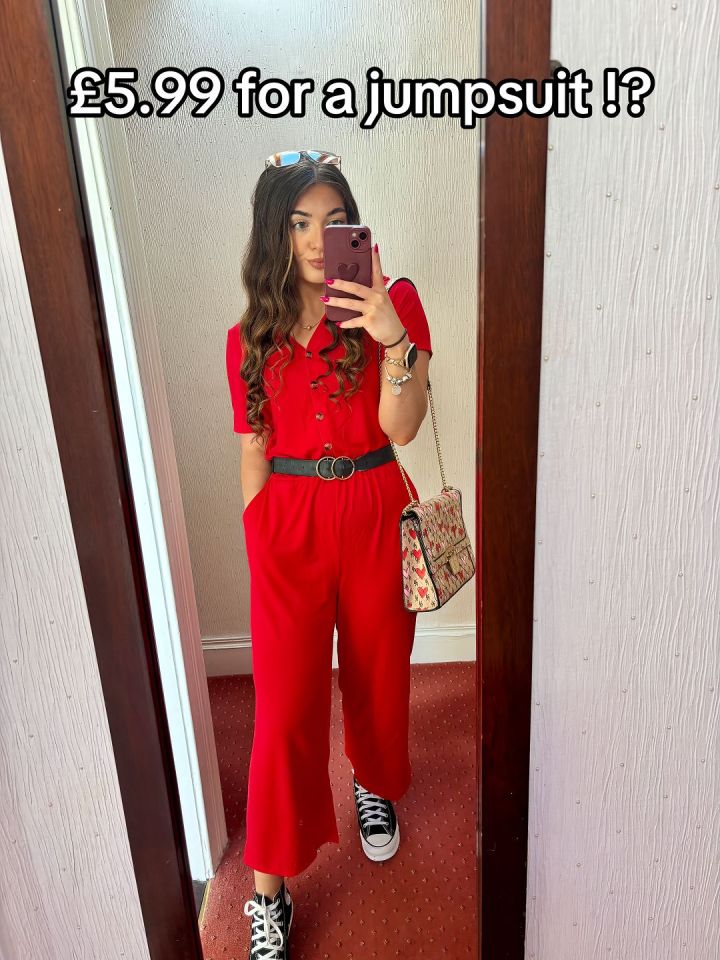 Woman in red jumpsuit taking a mirror selfie.