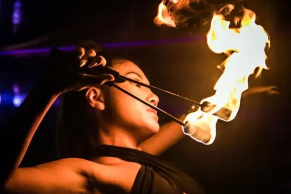 An image collage containing 1 images, Image 1 shows A fire dancer performing with torches