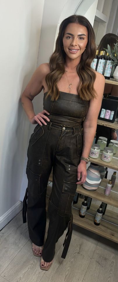 Woman in dark cargo pants and a brown top.