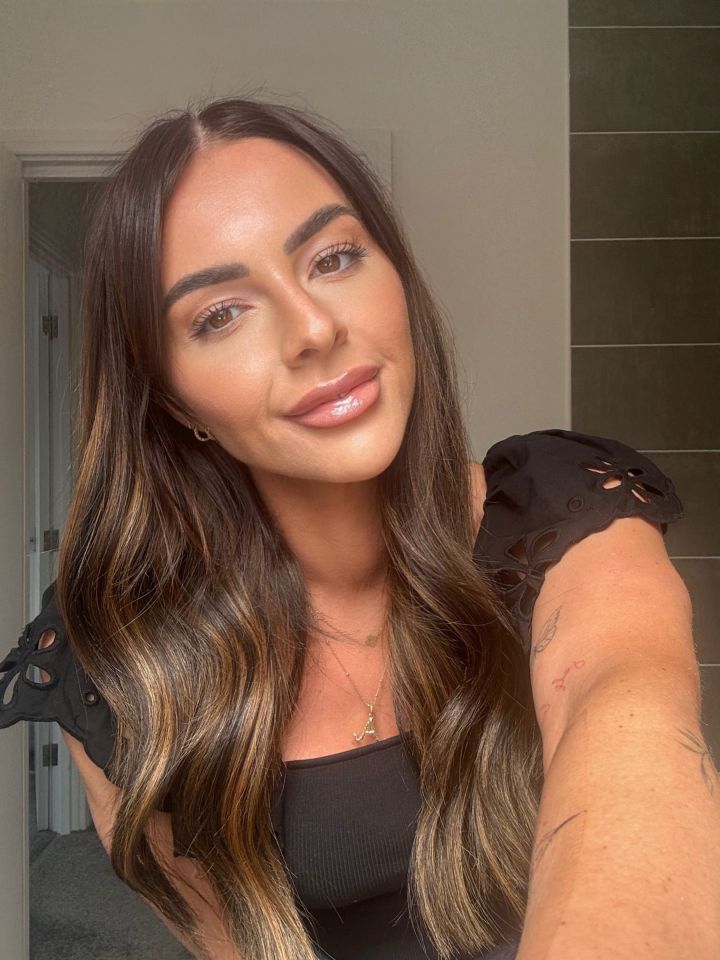 Close-up selfie of a woman with long brown hair and makeup.