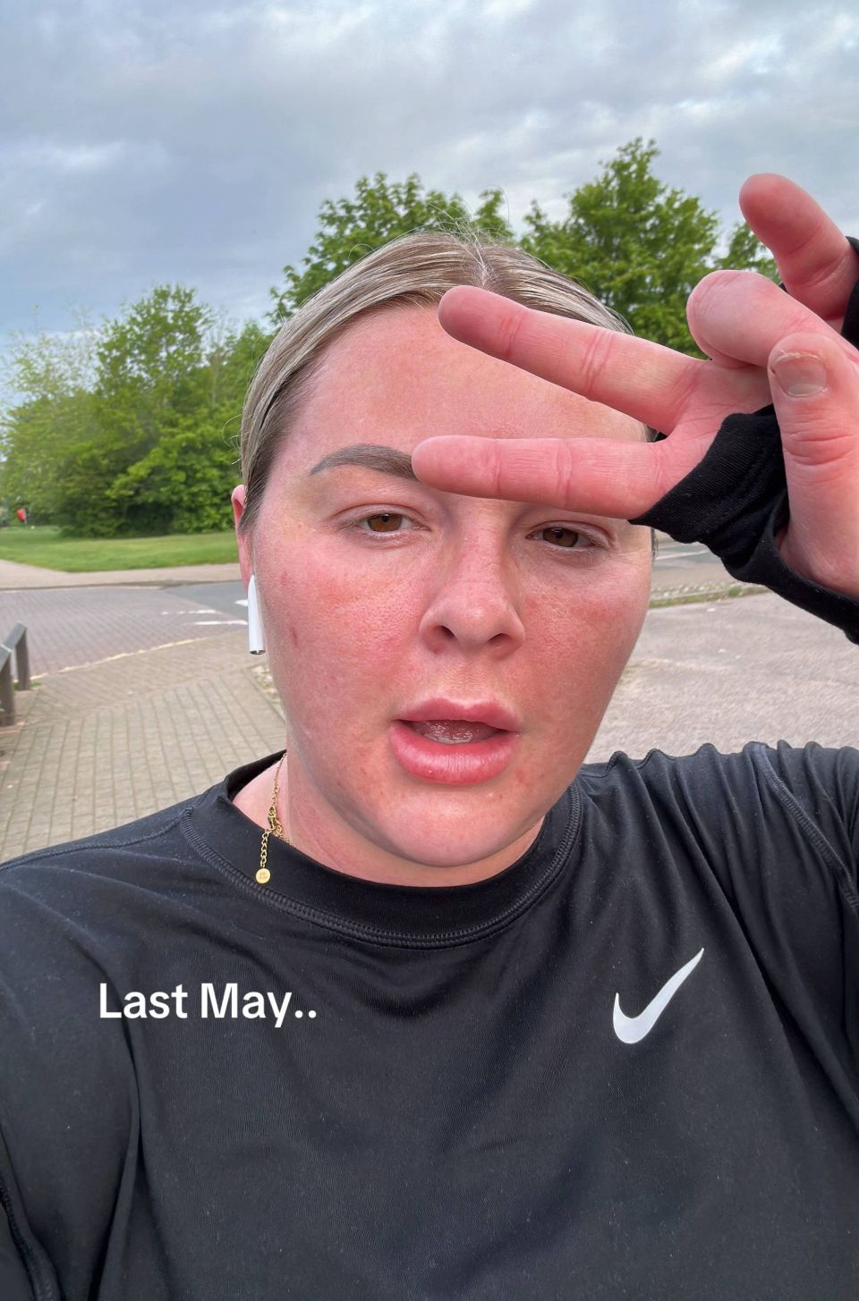 Woman in black Nike top, partially obscuring her face with her hand.