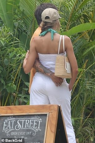 Zara showed off her toned physique in a white bandeau top and low-rise trousers, with a green bikini underneath, and carried her belongings in a Loewe basket bag