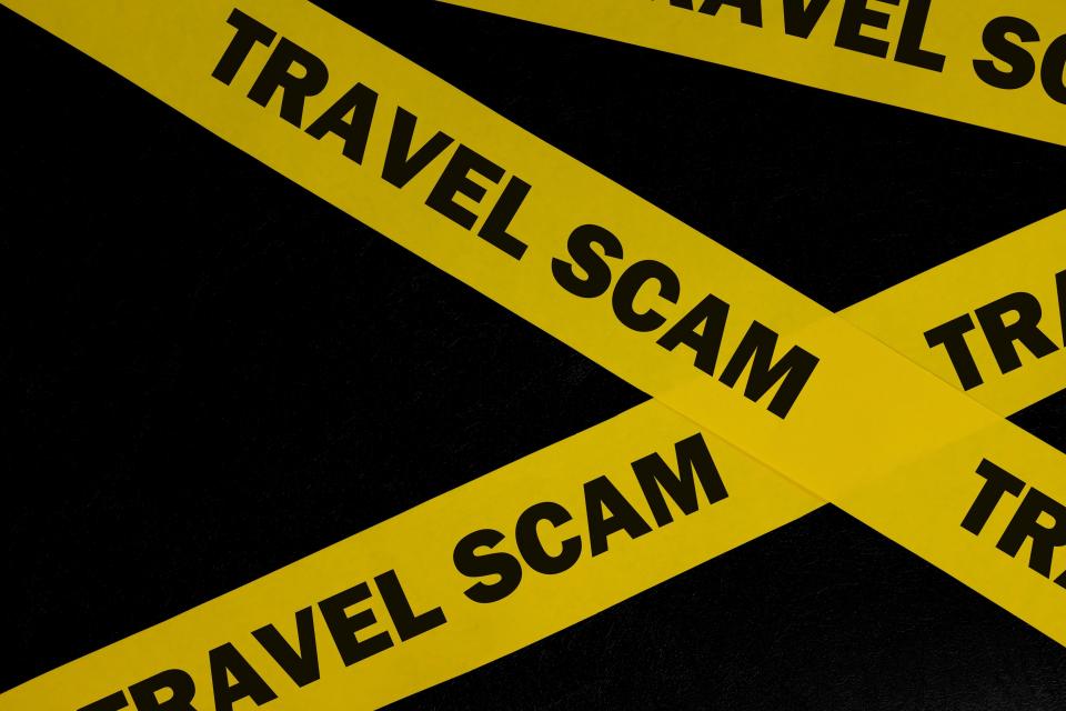 Yellow caution tape with the words "TRAVEL SCAM" printed on it.