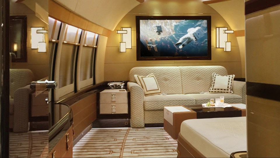 Luxury private jet cabin interior with couch and bed.