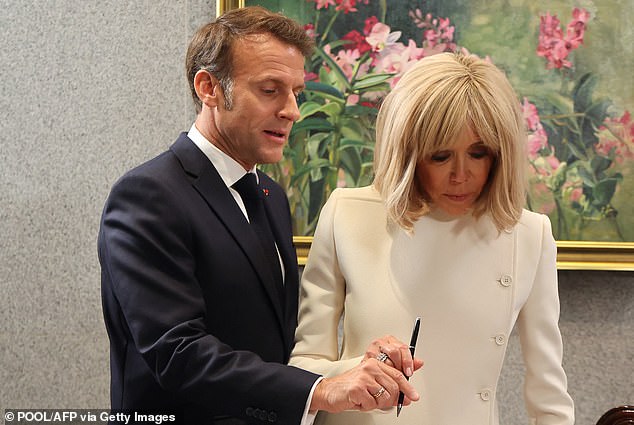 Emmanuel Macron and his wife Brigitte prepare to sign in a book at the Parliament House. 'When the pair sign a register they both cling to the pen,' Ms James noted
