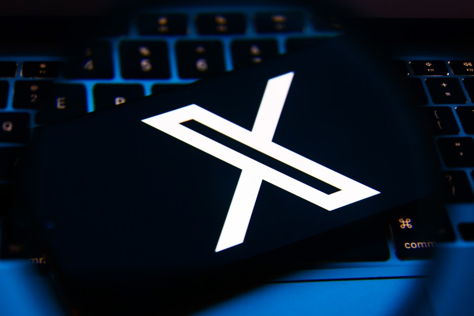 X logo on a phone screen above a keyboard.