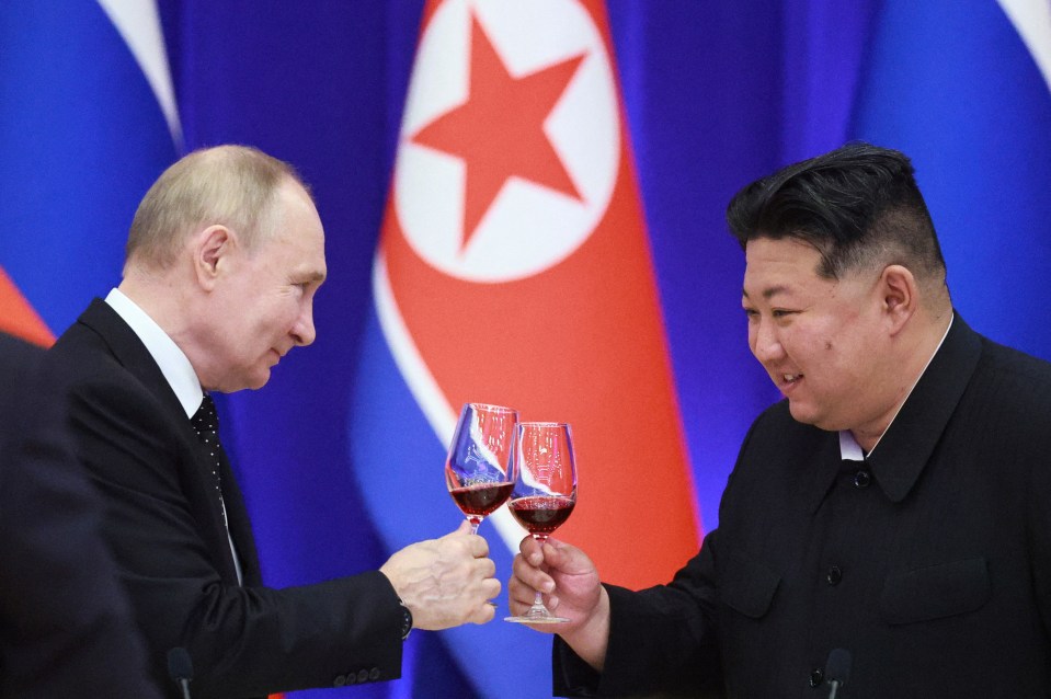 Vladimir Putin and Kim Jong Un toasting with wine glasses.