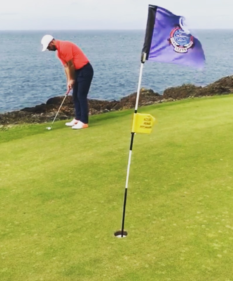 Golfer putting on a green overlooking the ocean.