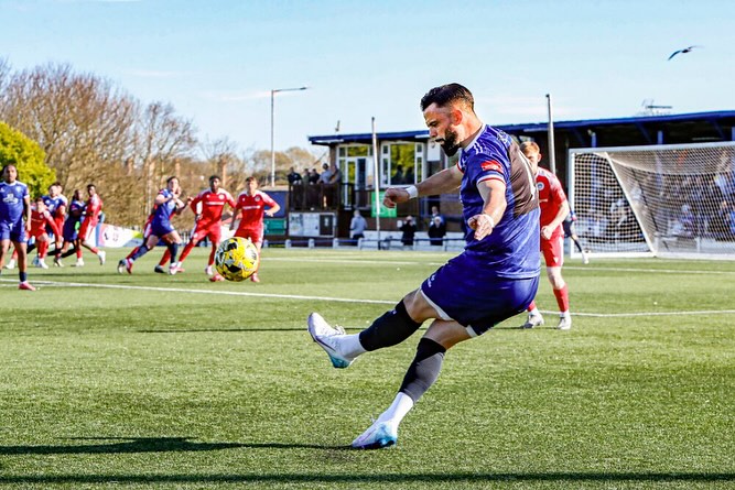 Soccer player kicking a ball during a game.